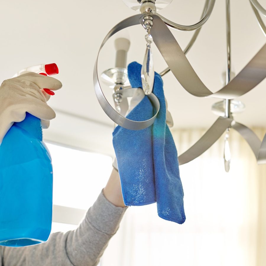 House cleaning, close-up of hands with rag detergent, cleaning and polishing lamp, chandelier