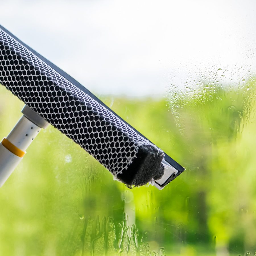 Window washing and home cleaning. A young woman sprays a detergent on a glass. Housework concept.